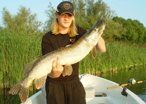 Visser met een gevangen snoek in een boot